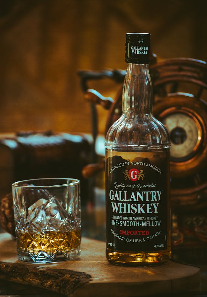 Close-up of Gallantry Whiskey bottle with glass on wooden surface, warm lighting.